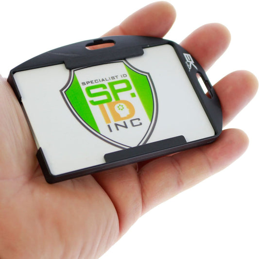 A person holds a Black EK Patriot Shielded RFID Blocking Two Card ID Badge Holder (10916) by EK USA displaying a white card with a green and orange "SP.ID INC" logo. Sold by Specialist ID.
