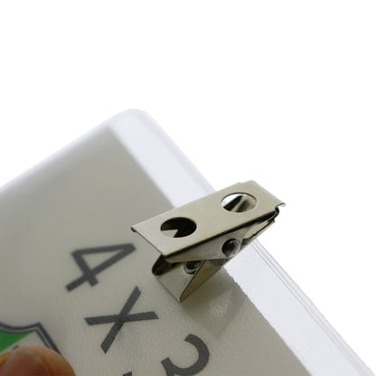 Close-up of a 4x3 Inch Clear Vinyl Horizontal Badge Holder with Clip (1810-1300) attached to the corner of a white rectangular object with printed text, including a partially visible "4X3".