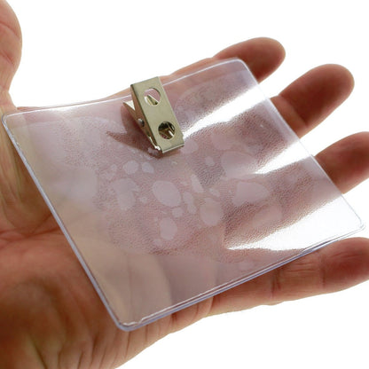 A 4x3 Inch Clear Vinyl Horizontal Badge Holder with Clip (1810-1300) is held in an open hand.