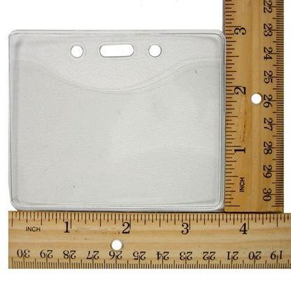 A Textured Horizontal Badge Holder (P/N 1815-1000) is placed next to two wooden rulers, one positioned horizontally and the other vertically, displaying measurements.