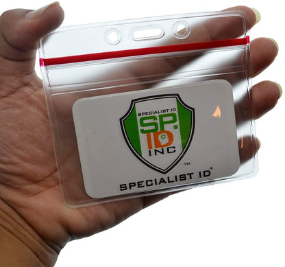 A hand holds a transparent, Heavy Duty Clear Vinyl Horizontal Badge Holder With Resealable Zip Top (1815-1010) with a logo displaying "Specialist ID SP INC" on a white card inside, ensuring your ID credentials stay secure.