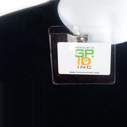 A black ID badge holder around a person's neck holds a Clear Vinyl Horizontal Badge Holder With Clip And Chain Holes (P/N 1815-1405) displaying the text "SPECIALIST ID" and the website "www.specialistid.com".