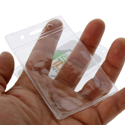 A hand holding a Standard Vertical Vinyl ID Badge Holder (1820-1050), with an empty slot for a credit card sized ID card visible through the transparent material. The holder boasts impressive durability.