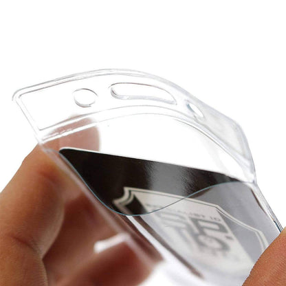 Close-up of a hand holding a Standard Vertical Vinyl ID Badge Holder (1820-1050) containing a black object with white text and graphics partially visible.