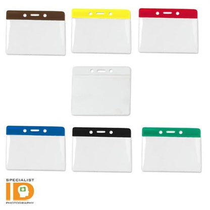 Assorted color-coded name badge holders with transparent pockets, arranged with one holder in the center surrounded by six others. The logo of "Specialist ID" is visible in the bottom left corner. These Government/Military Size Horizontal Vinyl Color-Bar Badge Holder (P/N 1820-110X) are perfect for government or military use.