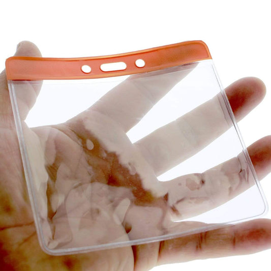 A hand holds an Extra Large Color Code Badge Holder for 4x3 Badges - Horizontal Vinyl with Color Bar (1820-120X), crafted from clear vinyl with an orange top edge and holes for attachment.