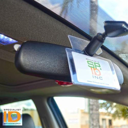 Rearview mirror with a Specialist ID badge and a Clear Rigid Vinyl Horizontal Parking Pass Vehicle Hang Tag Holder (1840-3650) attached, seen inside a car.
