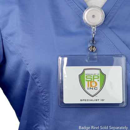 A Clear Heavy Duty Vinyl Horizontal Proximity Card Holder 1840-5017 is clipped to a blue uniform top, displaying a card with the logo "Specialist ID Inc." Text on the image states, "Badge Reel Sold Separately.