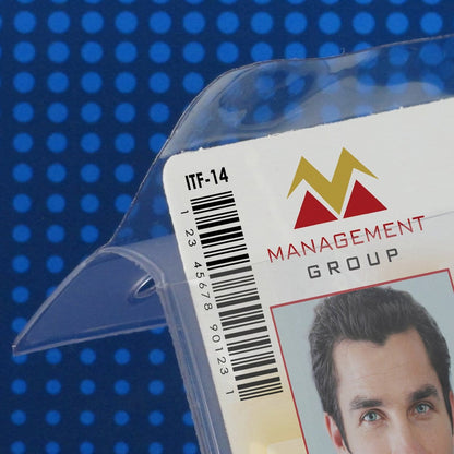 Close-up of a clear plastic package with a barcode, the text "ITF-14," and a partial view of a corporate identity card from "Management Group" featuring a man's photo. The card is securely placed in a Clear 2 7/8" X 4" Vinyl Vertical Large Badge Holder With Tuck-In Flap (P/N 1840-5150). Background is blue with dots.