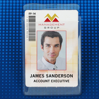 Photo of a name badge for "James Sanderson, Account Executive" with a photo of a man in a suit. The badge, enclosed in a Clear 2 7/8" X 4" Vinyl Vertical Large Badge Holder With Tuck-In Flap (P/N 1840-5150), is marked with "Management Group" and labeled "ITF-14".