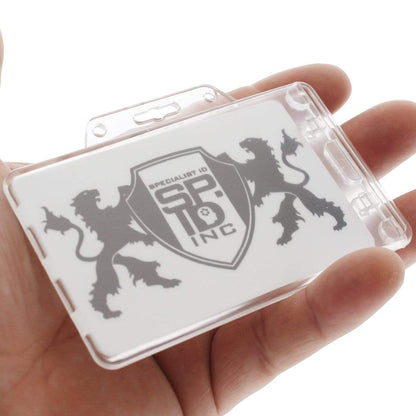 A hand holding a transparent plastic card holder with a logo featuring two lion silhouettes and a shield with the text "Specialist ID SPID Inc." The Clear Horizontal Permanent Locking Plastic Card Holder (P/N 1840-6040) combines both security and style, making it an ideal choice for professionals.