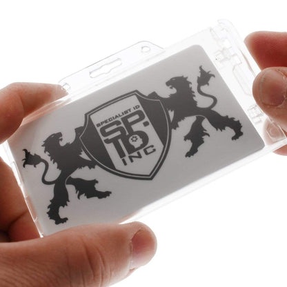 A close-up of hands holding a Clear Horizontal Permanent Locking Plastic Card Holder (P/N 1840-6040) with a card inside, displaying a logo featuring two lions and the text "Specialist ID SIC INC.