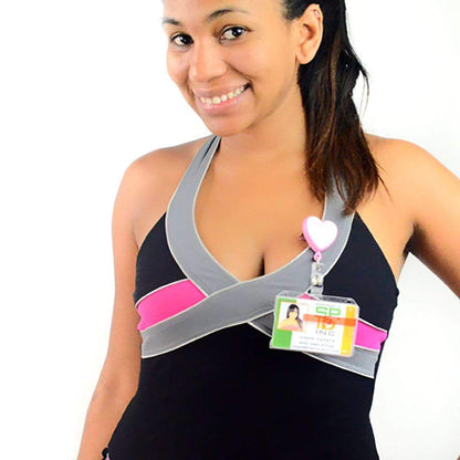 A woman smiling and wearing a black and grey top with a pink band. She has a lanyard with an ID badge holder, specifically the 2 Card Badge Holder with Slide (P/N 1840-6400), around her neck.