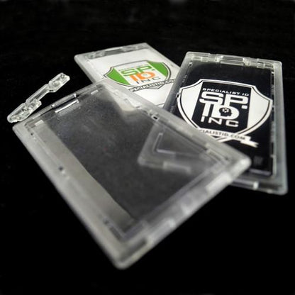 Three transparent plastic ID badge holders, including one Clear Vertical Locking Plastic Card Holder (P/N 1840-6630), are laid out on a black surface; two contain printed cards while the other remains empty.