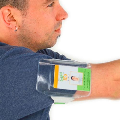 A person wearing a blue shirt has an Oversize Vertical Armband Badge Holder (1840-7110) strapped to their upper arm, displaying an ID card behind a heavy-duty vinyl cover. Sold by Specialist ID.