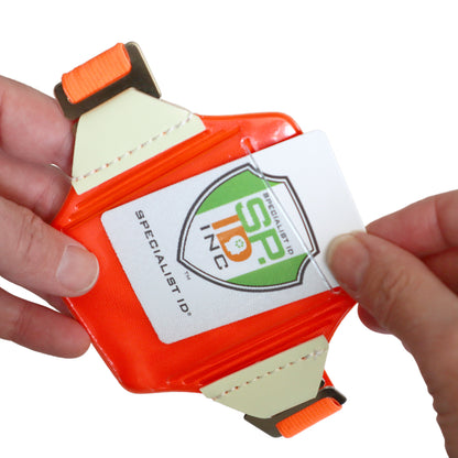 A person inserts a card labeled "Specialist ID Inc." into a Reflective Bright Orange Arm Badge Holder with Glow-in-the-Dark Tabs and Included Armband.