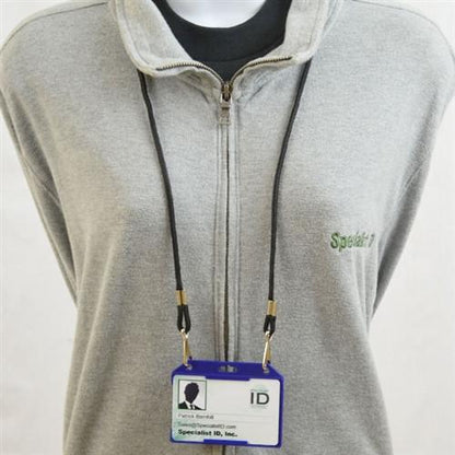 A person wearing a gray zip-up sweater with an ID badge in a Horizontal Open-Face Rigid Plastic Card Holder (1840-811X) around their neck. The badge displays a company name and the word "Specialist" embroidered on the sweater.