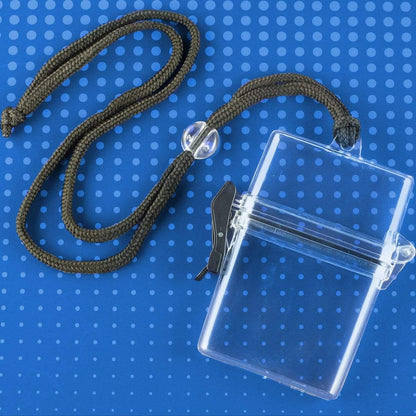 A Multi-Card Clear Rigid Water Resistant Holder (1840-9000/WPH-1) with a black latch and a black braided neck strap is lying on a blue polka-dot surface, doubling as a versatile water-resistant case.