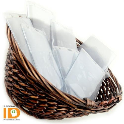 A wicker basket contains multiple white plastic sleeves with a "Special ID Photography" logo visible in the lower-left corner. These sleeves feature a clear front and back with two pockets for 4x5 and 4x3 photos, ideal for use as Two Pocket Event Badge Holder with 4x5 and 4x3 Sleeves - Clear Vertical Credential Holder (1860-4000).