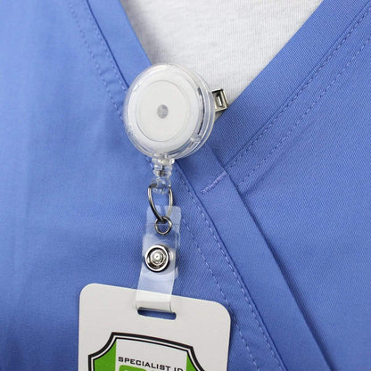 Close-up of a healthcare worker's blue scrub top, featuring an ID badge attached to a Translucent Badge Reel with Swivel Clip (P/N 2120-762X) on the collar. Sold by Specialist ID.