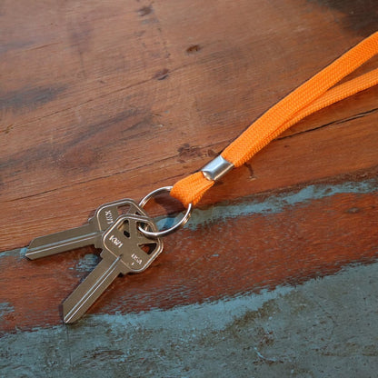 Two keys on a durable silver keyring are attached to a Flat Lanyard with Key Ring - 3/8 Inch Non Breakaway Neck Lanyard for Keys or ID (2135-365X), placed on a wooden surface. Sold by Specialist ID.