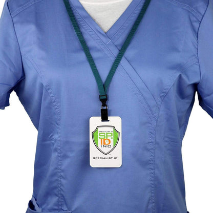 A person wearing blue scrubs with a green Premium Breakaway Lanyard with Bulldog Clip (2137-600X) displaying an ID badge holder labeled "Specialist ID" is shown from the shoulders to the waist.