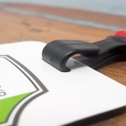 A black plastic clip secures a white rectangular card with a green triangle and partial text. The card, attached to a ***Wide 5/8" Lanyard with No Twist Plastic Hook (2138-478X)***, rests on a wooden surface.