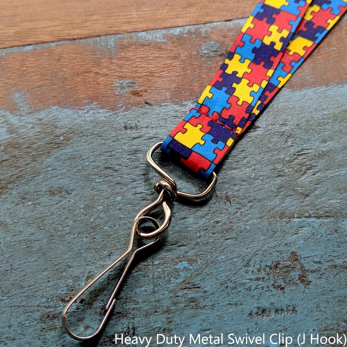 A colorful Autism Awareness Flat Breakaway Lanyard With Swivel Hook (2138-5281, 2138-5282) with a puzzle piece pattern, symbolizing Autism Awareness, ends in a heavy-duty metal swivel clip and is placed on a textured surface.