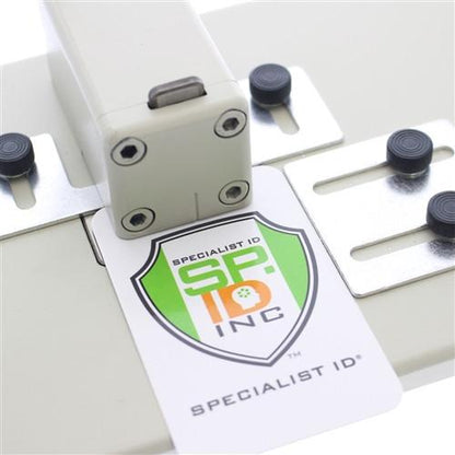 A Heavy Duty Table Top Slot Punch With Adjustable Guides (P/N SPID-9620) with a card displaying the logo 'SPECIALIST ID INC.' inserting into the PVC card punch slot.