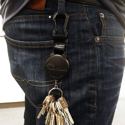 Person wearing dark blue jeans with a Key-Bak SecureIt Super Duty Gear Reel #488B-SDK clipped to their belt loop, holding multiple keys.