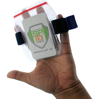 A hand holding a transparent Vertical Armband ID Badge Holders with Zipper Top (504-ARZB & 504-ARZW) with a Specialist ID card inside, attached to the wrist using a blue strap with Velcro fasteners.