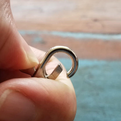 Close-up of a hand holding a Premium Metal Lobster Claw Clasp Hook Craft Findings - 1.5 Inch Clip with Trigger Snap and Round Eye Swivel D Ring, against a blurred background—a perfect tool for crafting and jewelry making.