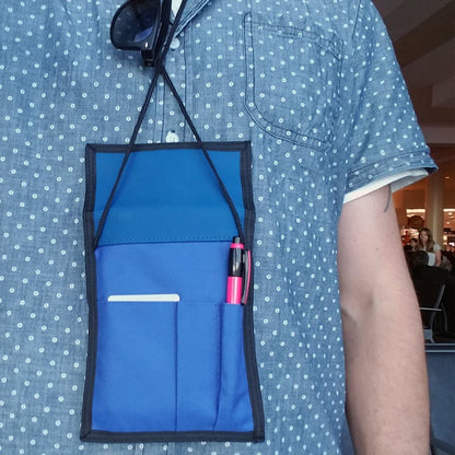 Person wearing a blue polka dot shirt with a Multi-Pocket Credential Neck Wallet with Lanyard (1860-300X) around their neck, holding a pink pen, a card, and sunglasses.