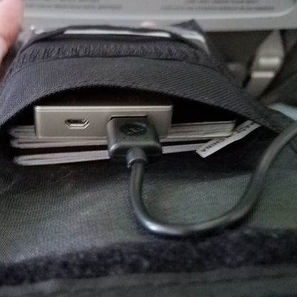 A close-up of a portable electronic device and a power bank stored inside a Multi-Pocket Credential Neck Wallet with Lanyard (1860-300X) with multiple pockets, featuring a USB cable connected to the device.