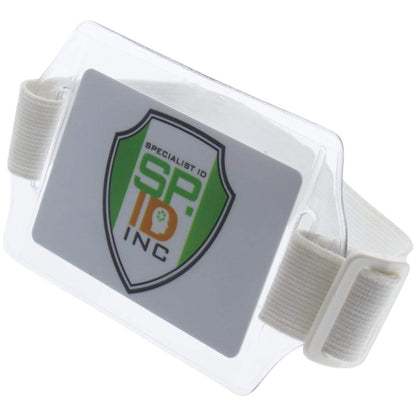 A horizontal arm ID badge holder (ABH-H) with a white strap is displayed, featuring a logo that reads "Specialist ID INC" on the card inside. The clear vinyl enclosure ensures your card stays visible and protected.