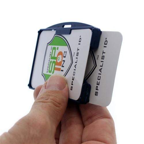 A hand is holding a Two Card Holder - Rigid Open-Faced (P/N AH-150) containing two cards with the label "Specialist ID." The Two Card Holder - Rigid Open-Faced (P/N AH-150) has a dark-colored frame.