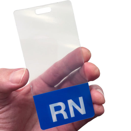 A person holds a transparent badge with a blue bottom section displaying the letters "RN." The badge is neatly attached to a Clear RN Badge Buddy Vertical with Color Border for Registered Nurses - Double Sided Print, making it an ideal Badge Buddy for nurses.