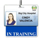 ID badge for Big City Hospital featuring a portrait photo of a woman and the name "Cindy Valencia" beneath the title "In Training." This laminated Teslin ID stands out in the bustling hospital environment, complete with an "IN TRAINING" Horizontal Badge Buddy with Blue border to ensure easy identification.