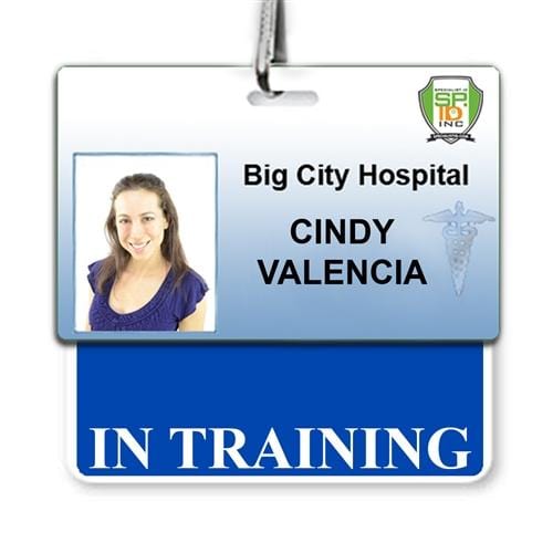 ID badge for Big City Hospital featuring a portrait photo of a woman and the name "Cindy Valencia" beneath the title "In Training." This laminated Teslin ID stands out in the bustling hospital environment, complete with an "IN TRAINING" Horizontal Badge Buddy with Blue border to ensure easy identification.