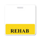 A label with a white background and a yellow area at the bottom features the word "REHAB" in black, capitalized letters, resembling a REHAB Horizontal Badge Buddy with Yellow Border often seen in a hospital setting.