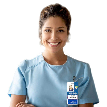 A smiling person wearing a light blue nursing uniform stands in a bustling hospital setting, their name badge clipped to their shirt reads "Cindy Valencia, Student Nurse," alongside a STUDENT NURSE Vertical Badge Buddy with Color Border.