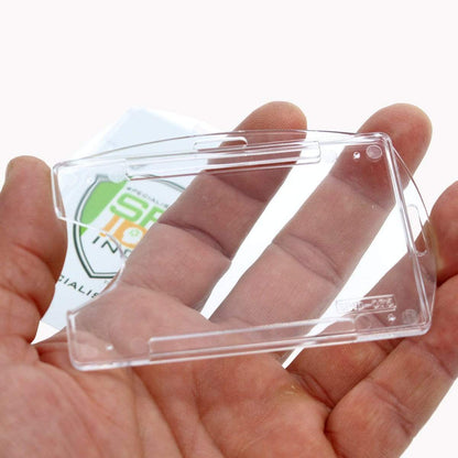 A hand holding a transparent polycarbonate cover, possibly a protective case for electronic devices, with green and white packaging visible in the background. The adaptable slot holes make it perfect as a Crystal Clear Rigid Open-Faced Single ID Card Holder (P/N SPID-075).