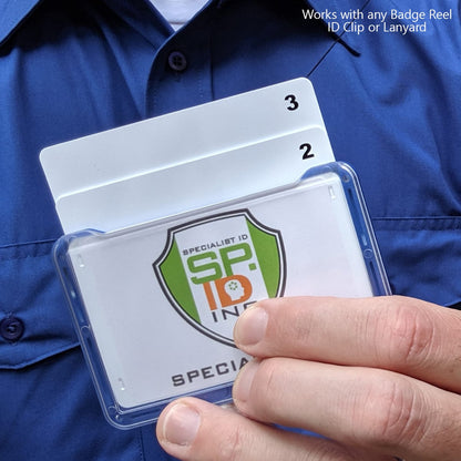 A person in a blue shirt holds a 3 Card Horizontal ID Badge Holder B-Holder containing multiple cards with a logo. Text on the image reads, "Works with any Badge Reel ID Clip or Lanyard.”