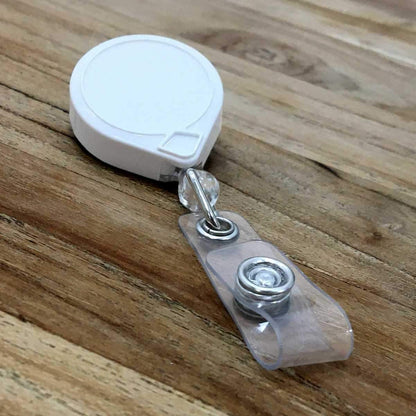 A MINI-BAK #66 White Retractable Reel with 36” Nylon Cord, Vinyl ID Strap and Swivel Clip 0066-005 lies on a wooden surface, featuring a durable nylon cord for added strength.