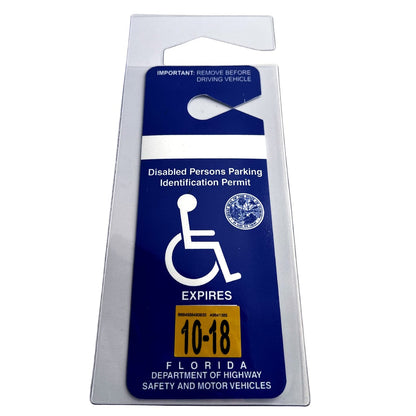 A Specialist ID Handicap Hang Tag Holder (SPID-1120) displays a blue Disabled Persons Parking Identification Permit with a wheelchair symbol, a Florida seal, and an expiration date of October 2018. This rearview mirror accessory advises removal before driving.