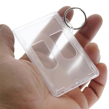 A clear, rectangular plastic keychain held in a person's hand, featuring an empty slot for inserting a picture or card. This durable **Two Card Vertical Clear Rigid Plastic Fuel Card and Badge Holder with Keychain (SPID-1220)** doubles as a badge holder, ensuring your essentials are secure and always within reach.