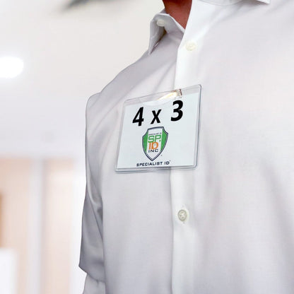 Close-up of a person wearing a white shirt with a 4 x 3 Horizontal Event Badge Holder with Clothing Friendly Bulldog Clip - Clear Vinyl, Horizontal & Durable (SPID-1440) displaying a card labeled "4 x 3" and "Specialist ID," attached using a clothing-friendly bulldog clip.