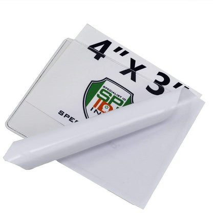 A sheet of white E-Z Ink photo paper is partially peeled back, revealing a Large 4 x 3 Adhesive Badge Holders with Sticky Back - Clear Vinyl Parking Pass Holders for Windshield (CE-4P) with a colored logo and text, similar to the inserts found in clear vinyl parking pass holders.