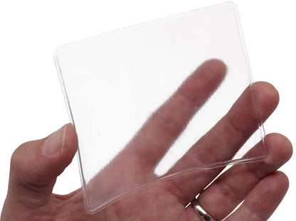 A hand holding a clear, rectangular Large 4 x 3 Adhesive Badge Holders with Sticky Back - Clear Vinyl Parking Pass Holders for Windshield (CE-4P) with rounded corners.