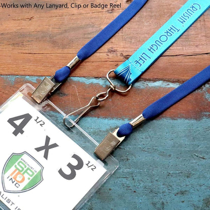 Laminated ID badge with a clip and blue lanyard attached, lying on a wooden surface. Text on the ID badge reads "4x3 Extra Large Badge Holder - USA MADE Plastic Horizontal 4 1/2 x 3 1/2 Card Protector for Conference, Trade Show Events (SPID-1590)." The background has text promoting the compatible lanyard feature and highlights that the durable clear badge holders are made in the USA.